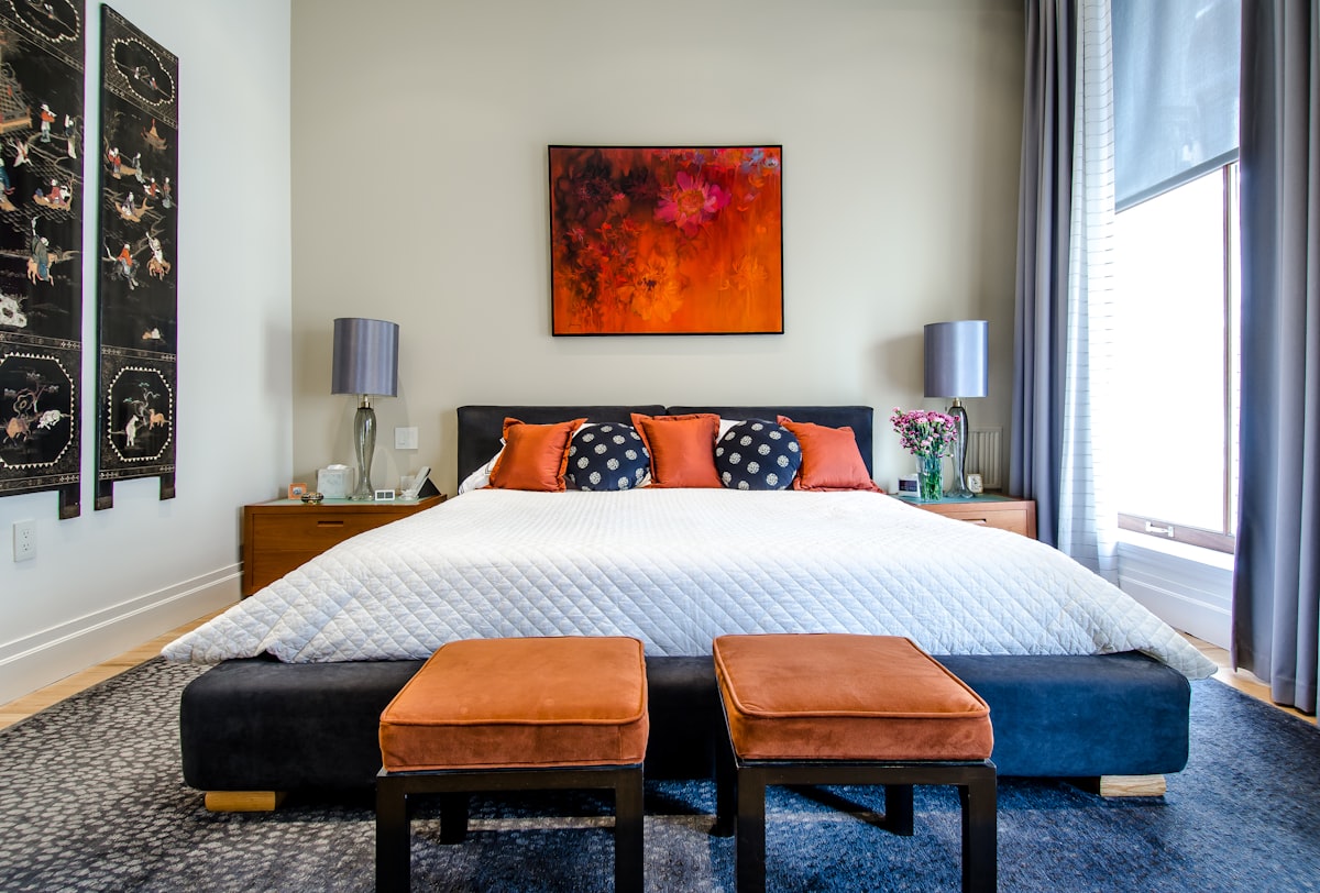 A bedroom with soft lighting and a white noise machine on a nightstand