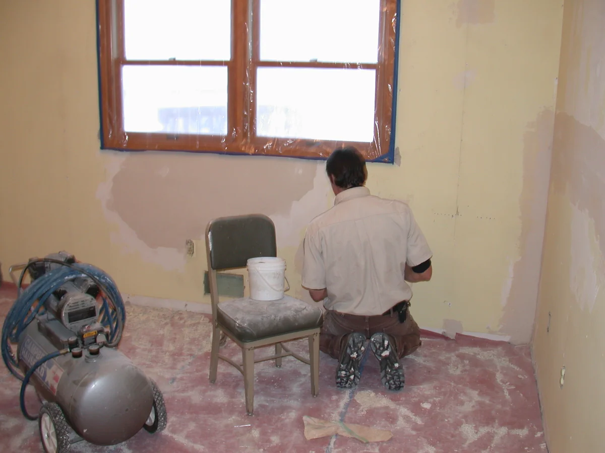 Hand applying joint compound to patch a small drywall hole